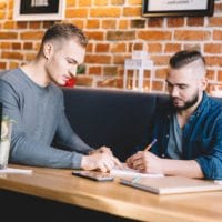 Two young men sitting in a cafe, discussing.