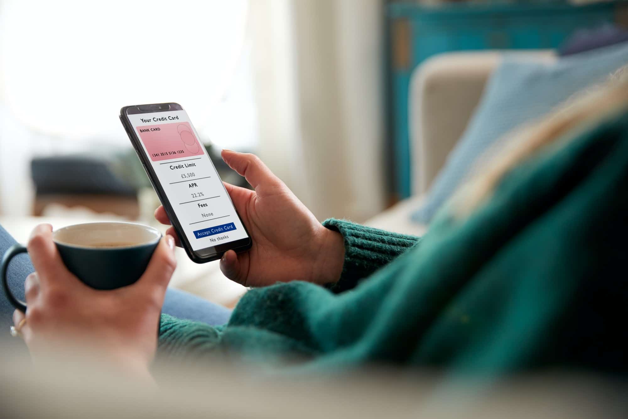 Close Up Of Woman Applying For Credit Card Online Using Mobile Phone At Home